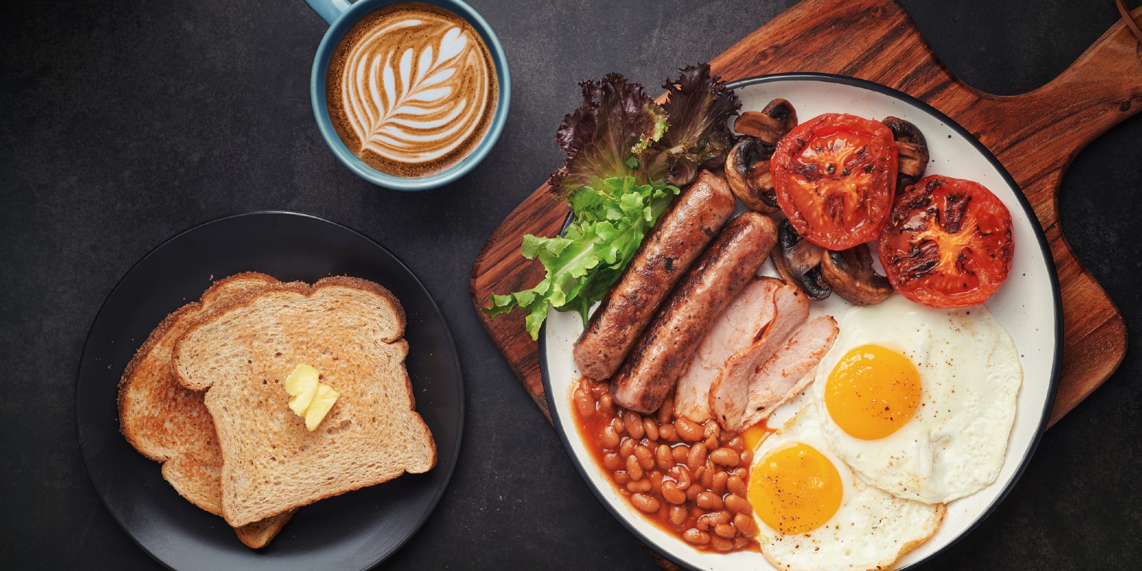 typisches englisches frühstück mit baked beans, würstchen, spiegelei, toast und butter